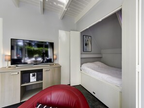 A compact room with a TV, a bed, a red chair, and a small desk with speakers. - Tranquil Getaway in Dalfsen (Dalfsen)