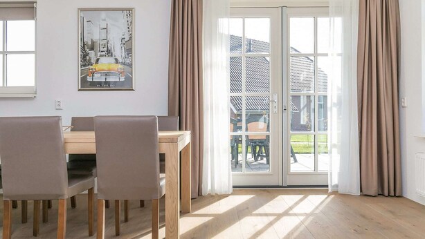A dining area with a table and chairs, a framed picture on the wall, and a sliding glass door leading to an outdoor area. - Villa Near Forest Trails (Hollandscheveld)