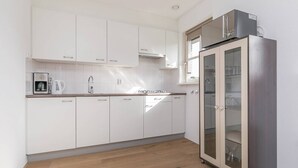 A modern kitchen with white cabinets, a stainless steel refrigerator, and a built-in oven. - Villa Near Forest Trails (Hollandscheveld)