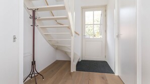 A staircase with a coat rack, a white door, and a radiator. - Villa Near Forest Trails (Hollandscheveld)