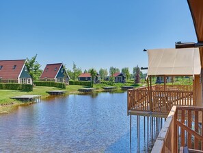 A lakeside view with houses, a wooden deck, and a clear sky.