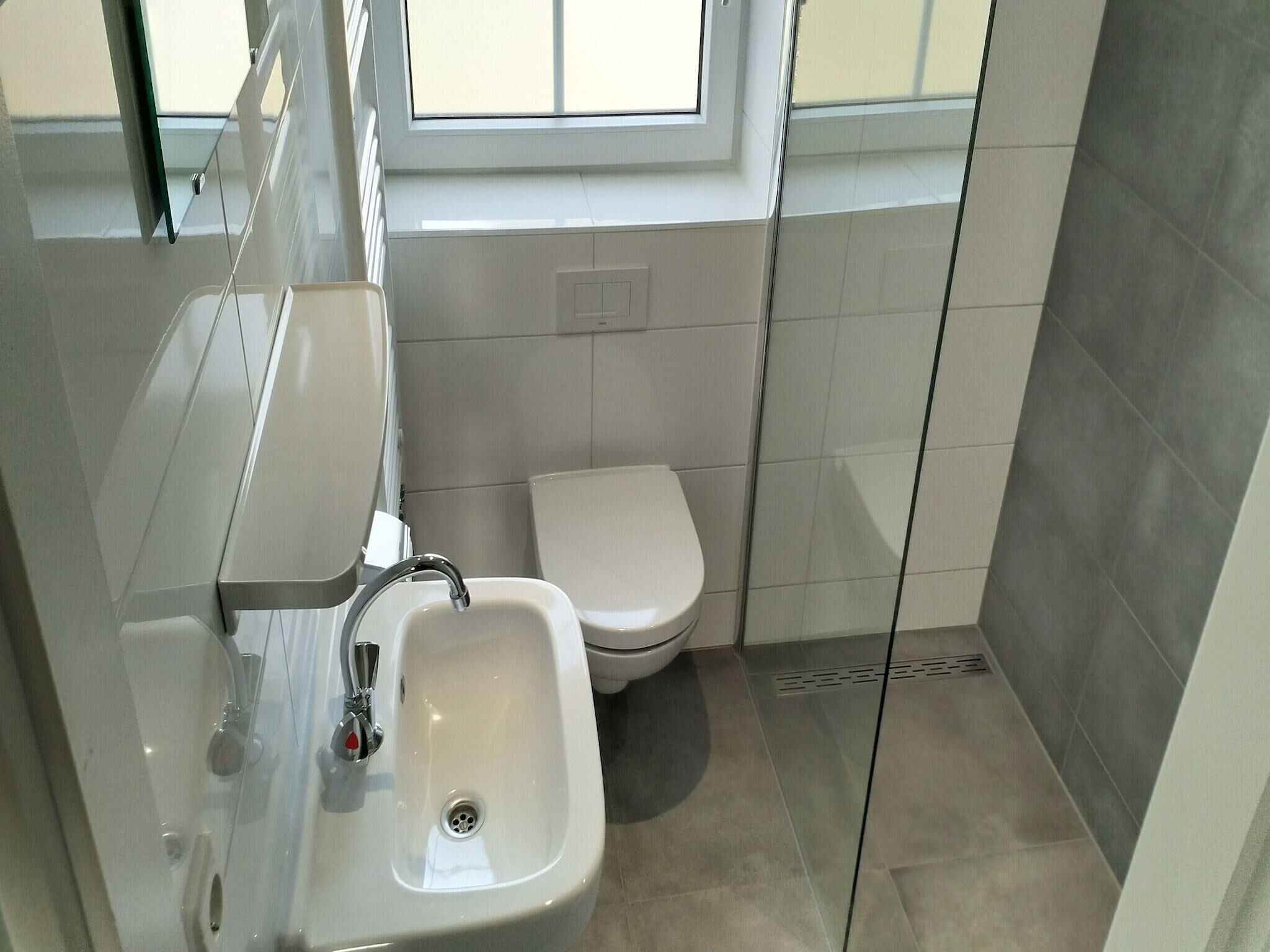 A modern bathroom with a sink, toilet, and a window.