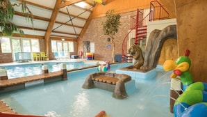 An indoor swimming pool with slides and a play area for children, surrounded by wooden beams and brick walls. - Spacious Villa in a National Park (Paasloo)