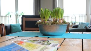 A metal bowl with green plants on a wooden table with magazines. - Holiday Home in Nijeberkoop near Nature (Nijeberkoop)