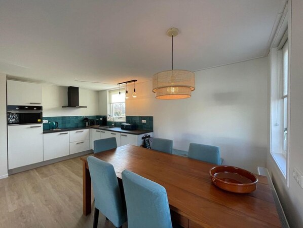 A modern kitchen with white cabinets, a black oven, and a window above the sink.