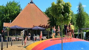 A beach with a colorful slide and a building with a red-tiled roof in the background.