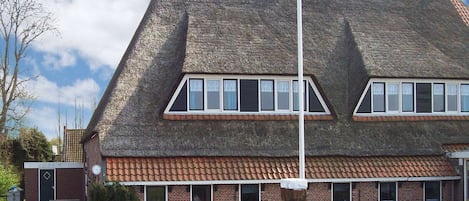 A two-story building with a steeply pitched roof, a brick facade, and a flagpole.