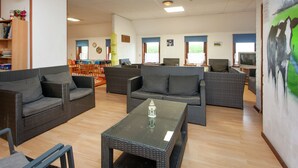 A spacious living area with wicker furniture, a glass coffee table, and a painting on the wall. - Farmhouse in Holwerd near the Sea (Holwerd)