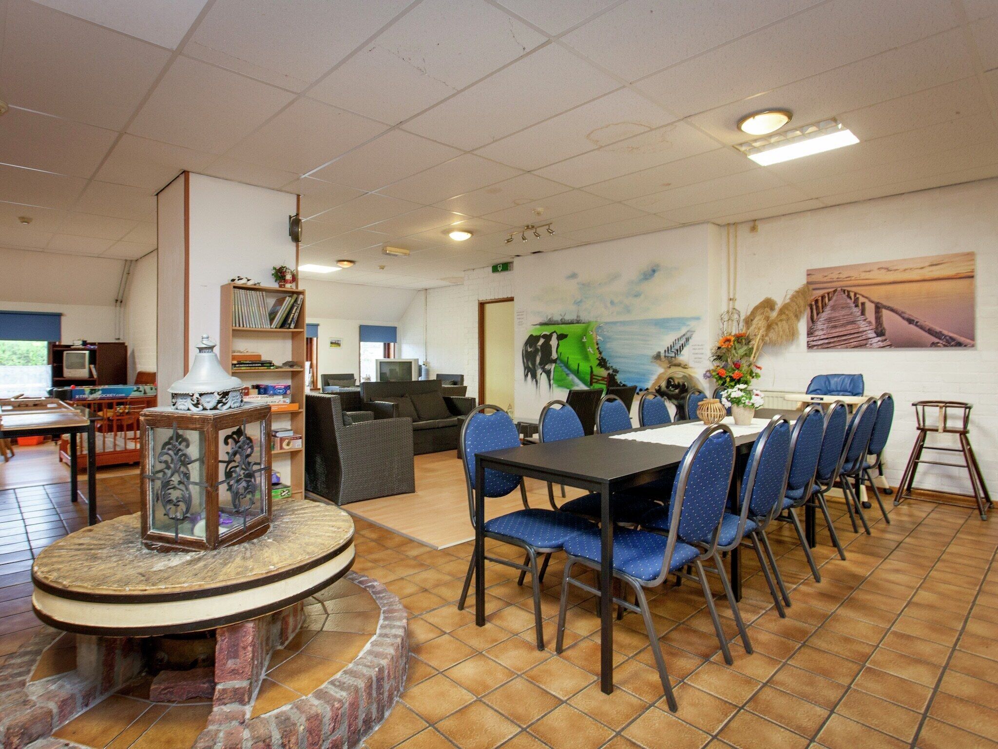 A dining area with a round table, blue chairs, and a mural on the wall.