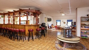 A bar area with stools, a wooden counter, and a brick fireplace. - Farmhouse in Holwerd near the Sea (Holwerd)