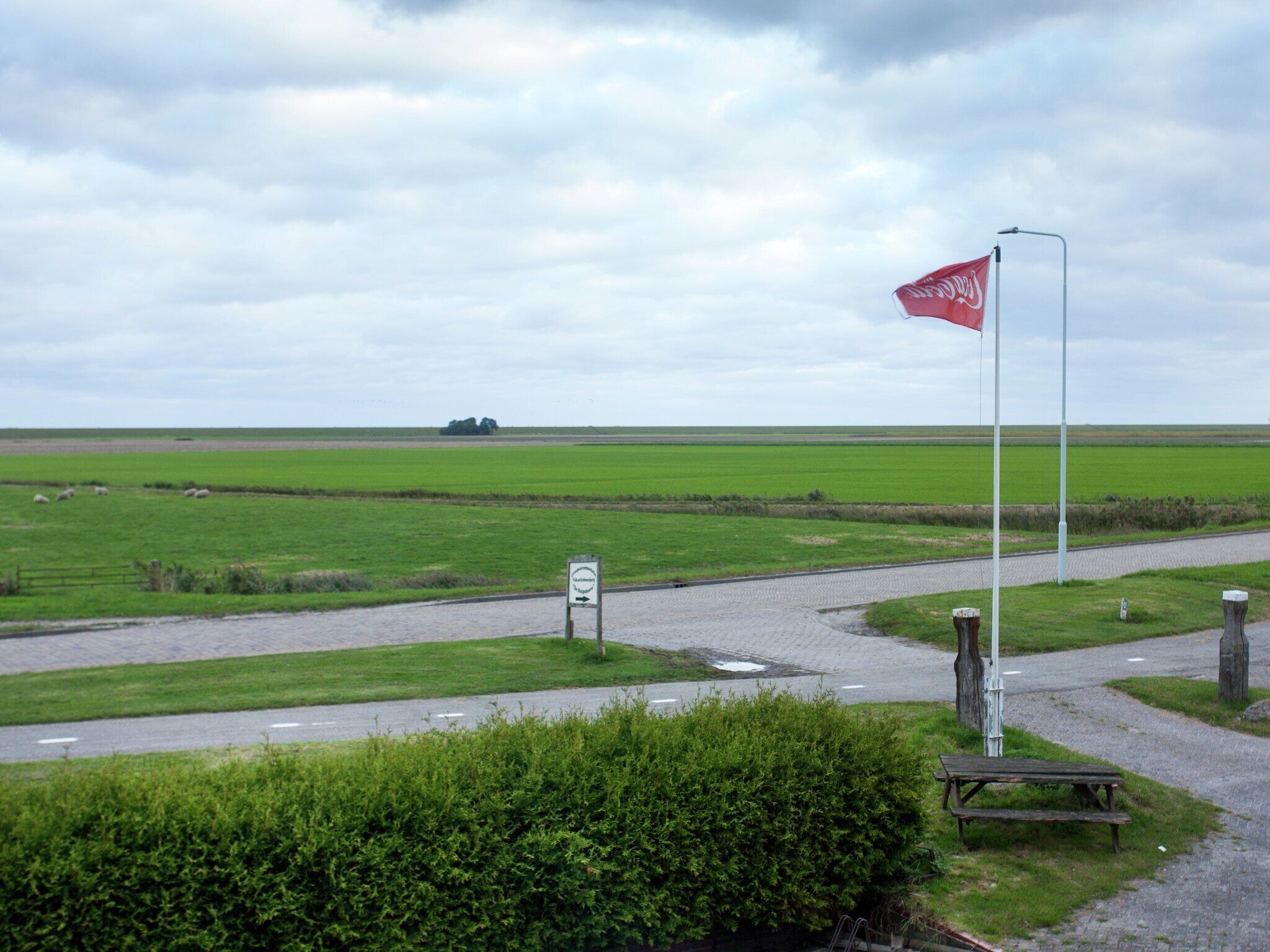 Landskab med flag på flagstang, et vejskilt og et picnicbord.