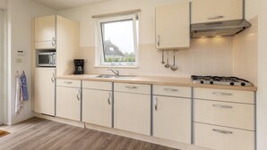 A modern kitchen with a gas stove, microwave, and stainless steel sink.