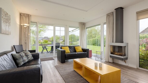 A modern living room with a black leather sofa, a wooden coffee table, and a fireplace.