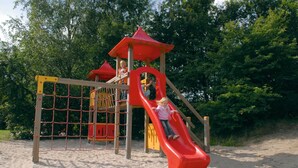 A playground with a red slide and climbing structures. - Cozy House nr Drents-Friese (Hoogersmilde)