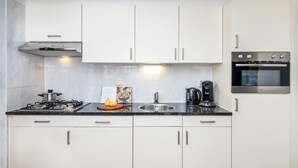 A modern kitchen with white cabinets, a stainless steel stove, a coffee maker, and a built-in oven. - Cozy House nr Drents-Friese (Hoogersmilde)