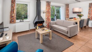 Una sala de estar moderna con chimenea, un sofá, una mesa de comedor y vistas al exterior.