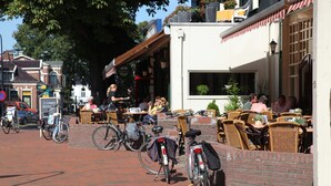 An outdoor café with wicker furniture and bicycles parked nearby. - Cozy House Surrounded by Nature (Tynaarlo)