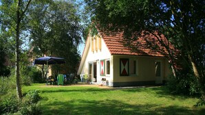A house with a red-tiled roof, a small porch, and a lawn. - Cozy House Surrounded by Nature (Tynaarlo)