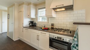 A modern kitchen with white cabinetry, a gas stove, an oven, and a window above the sink.