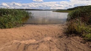 Una spiaggia sabbiosa che si protende verso un lago calmo, con sponde erbose.