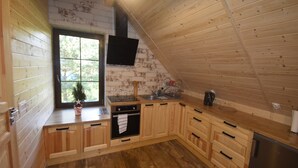 Una cucina compatta con mobili in legno, forno integrato e frigorifero in acciaio inossidabile.