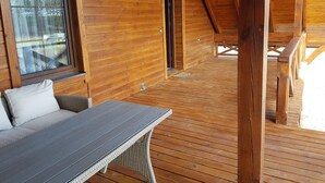 Una baita di legno con un balcone, un tavolo e un divano.