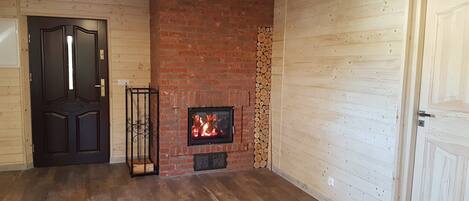 A room with a brick fireplace, wooden walls, and a wooden door.