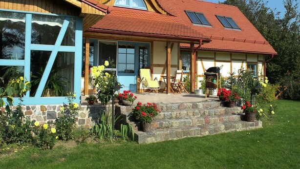 A house with a sloped roof, large windows, and a stone foundation. - Seaside Villa with Sauna (Karwieńskie Błoto Drugie)