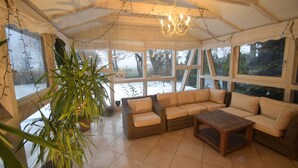 A cozy, well-lit room with large windows, a chandelier, and comfortable seating. - Seaside Villa with Sauna (Karwieńskie Błoto Drugie)