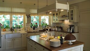 A spacious kitchen with white cabinetry, a large island, and a view of greenery through the windows. - Seaside Villa with Sauna (Karwieńskie Błoto Drugie)