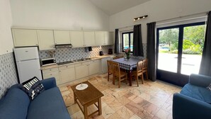 Un espace de vie compact comprenant un coin cuisine, un coin repas avec une table et des chaises, et un canapé.
