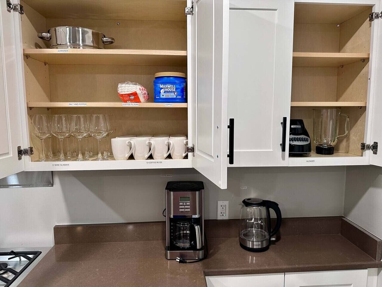 A kitchen with a coffee maker, a blender, and a coffee pot on the counter.