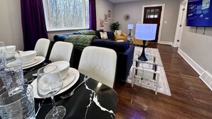 A dining area with a table set for four, a ceiling fan, and a television in the background. - Peaceful Giant House close to city (Carnegie)