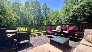 An outdoor deck with wicker furniture, a glass-top table, and a wooden railing. - Peaceful Giant House close to city (Carnegie)