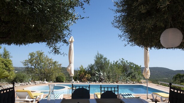 Un espace aménagé au bord de la piscine, avec des chaises longues, une table et des parasols.
