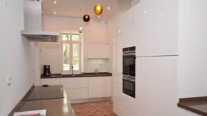 Une cuisine moderne avec des meubles blancs, un four encastré et une machine à café.