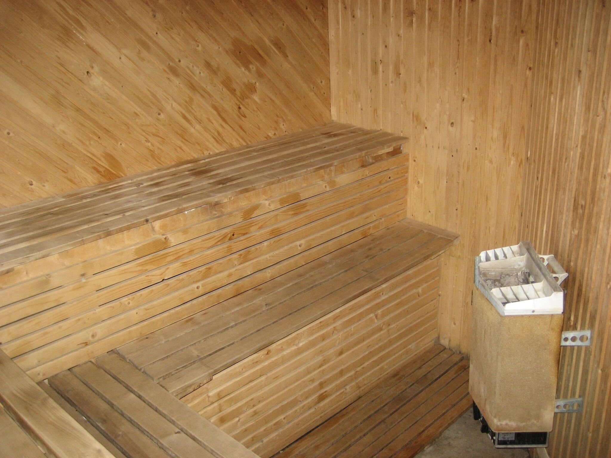 A sauna with wooden benches and a metal heater.