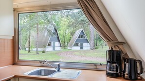 A kitchenette with a window view of two treehouses. - Bungalow in Bospark 't Wolfsven near Nature (Mierlo)