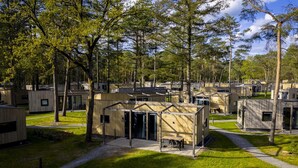 A campground with multiple RV-style cabins, a central building with a covered patio, and a well-maintained grassy area. - Bungalow in Bospark 't Wolfsven near Nature (Mierlo)