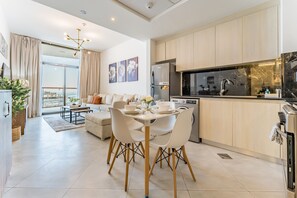 A modern kitchen with a dining area, light wood cabinets, and a large window. - Community View 1BR with Balcony Near Downtown Dubai, Binghatti Avenue, Al Jaddaf (Dubai)
