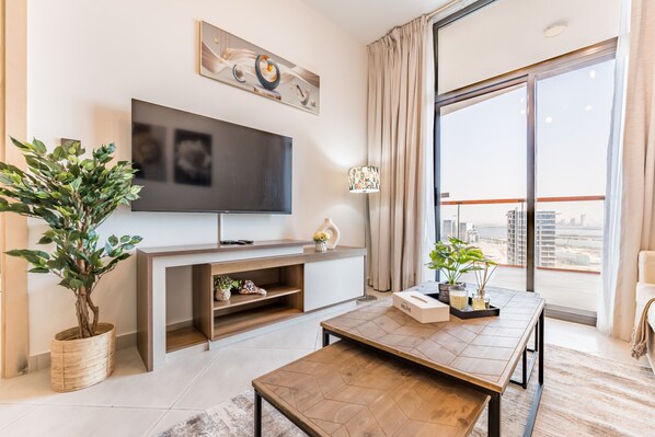 A modern living room with a flat-screen TV, a wooden coffee table, and potted plants.