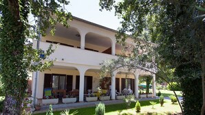 A two-story building with a covered outdoor seating area, potted plants, and a well-maintained garden.