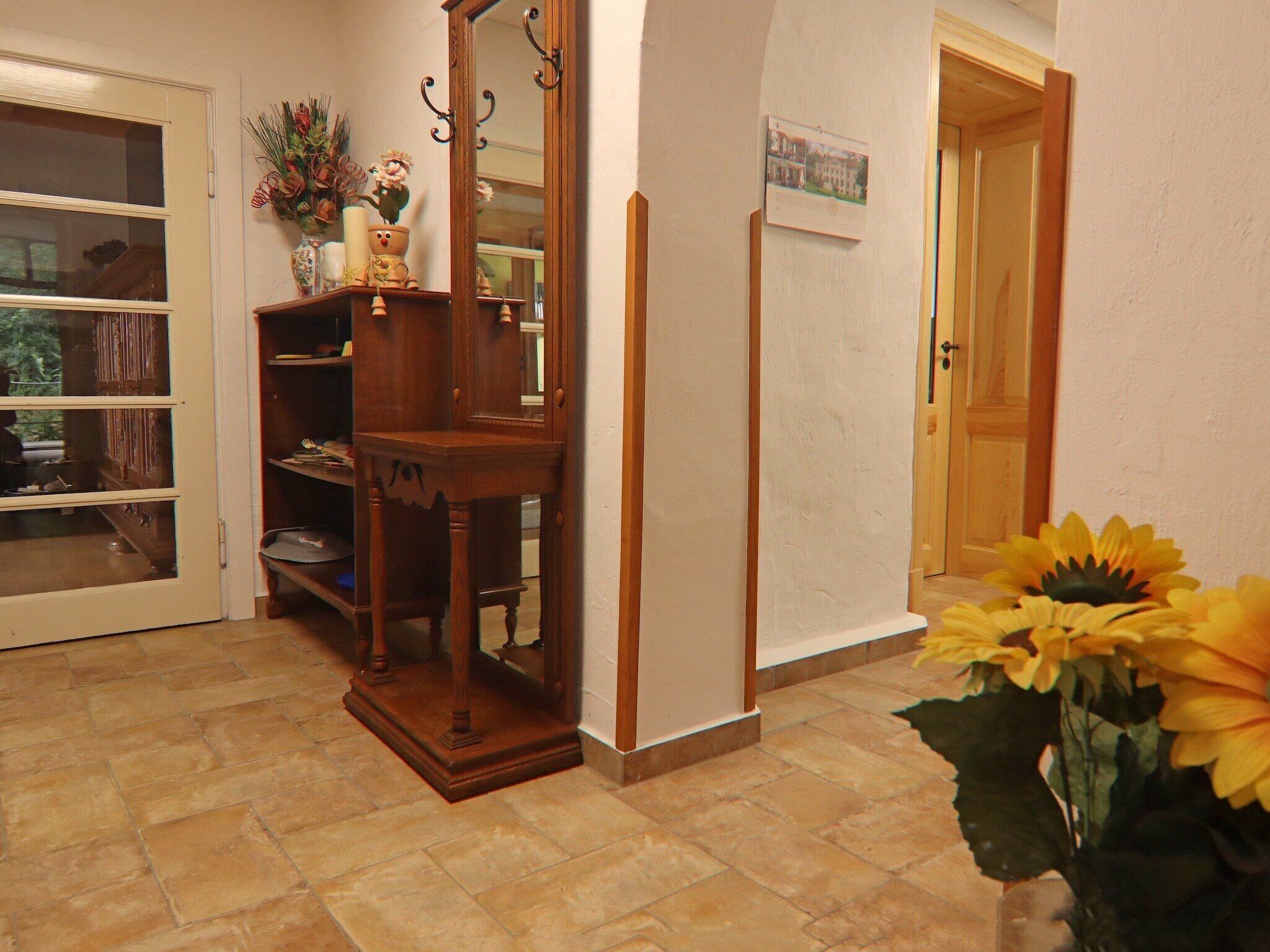 A hallway with a wooden cabinet, a mirror, and a door.