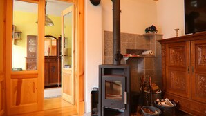 Une pièce dotée d’un poêle à bois, de meubles en bois et d’une porte donnant sur une autre pièce.