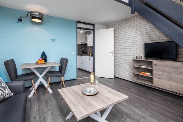 A modern living space with a dining area, a kitchen, and a TV.
