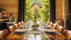 A wooden dining table set for six with wine glasses, plates, and a centerpiece. - Incredible Sunset Views | Organic Decor | Arcades (Sevierville)