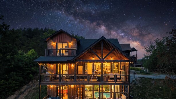 A two-story wooden cabin with a balcony, a pool, and a starry night sky. - Incredible Sunset Views | Organic Decor | Arcades (Sevierville)