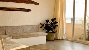 Una sala moderna con un sofá seccional color beige, un tapete tejido y una planta en maceta.