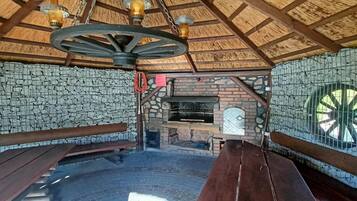 Un interior rústico de madera con pared de piedra, un horno de ladrillo y bancos de madera.