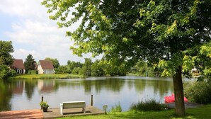 A serene lakeside setting with a wooden dock, a bench, and a small boat.